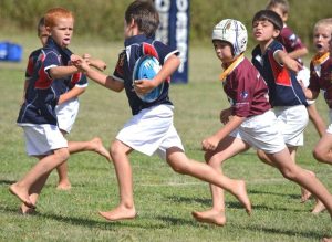 Boys playing rugby barefoot