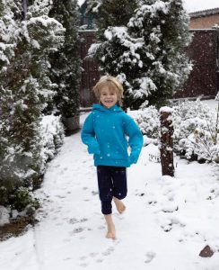 Boy smiling while walking barefoot in snow